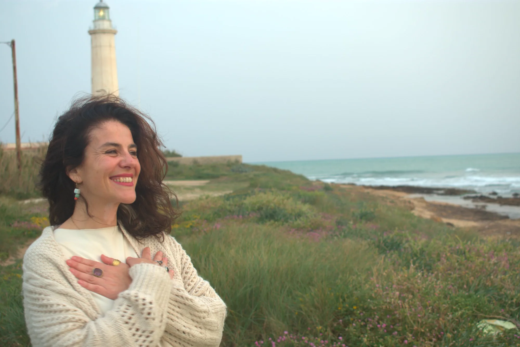 Sofia Cricchio sorride davanti al mare con un faro alle spalle